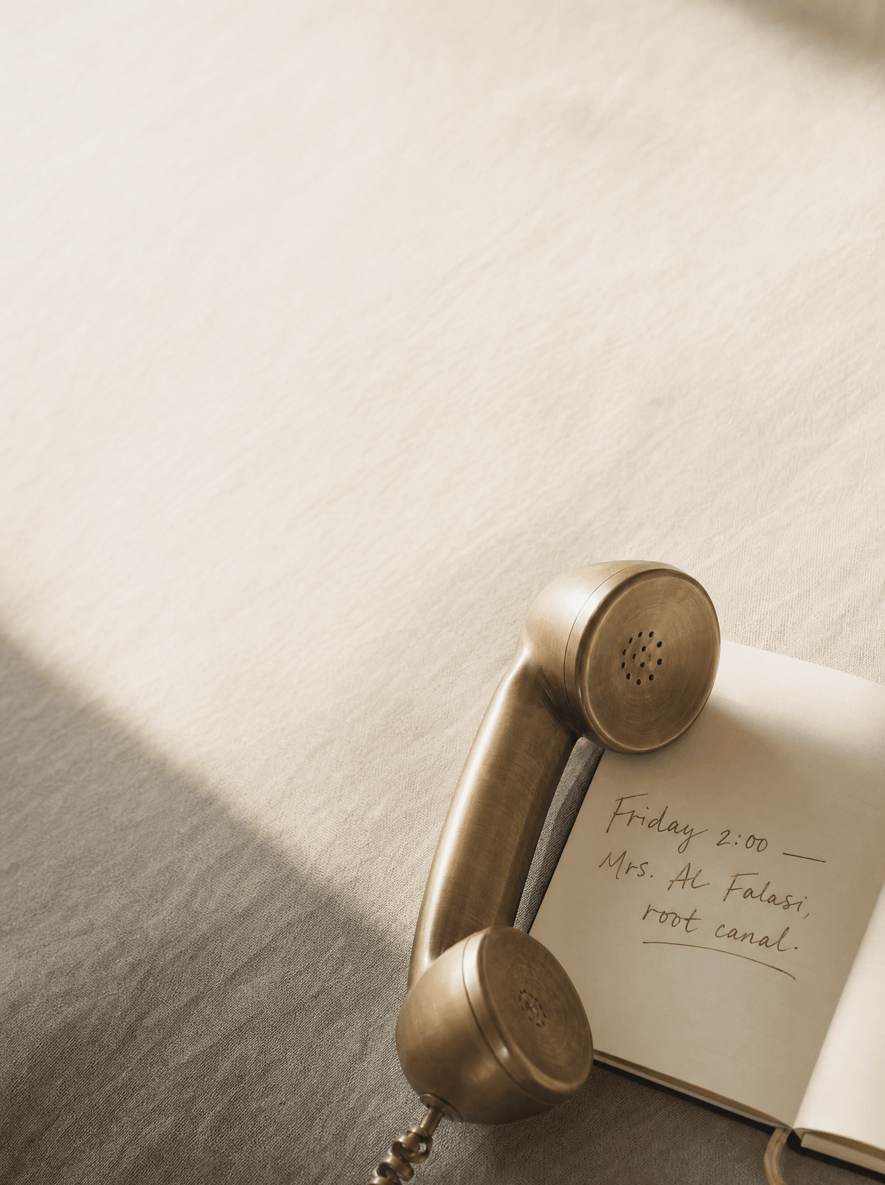 Brushed brass receiver on linen, beside a handwritten appointment note